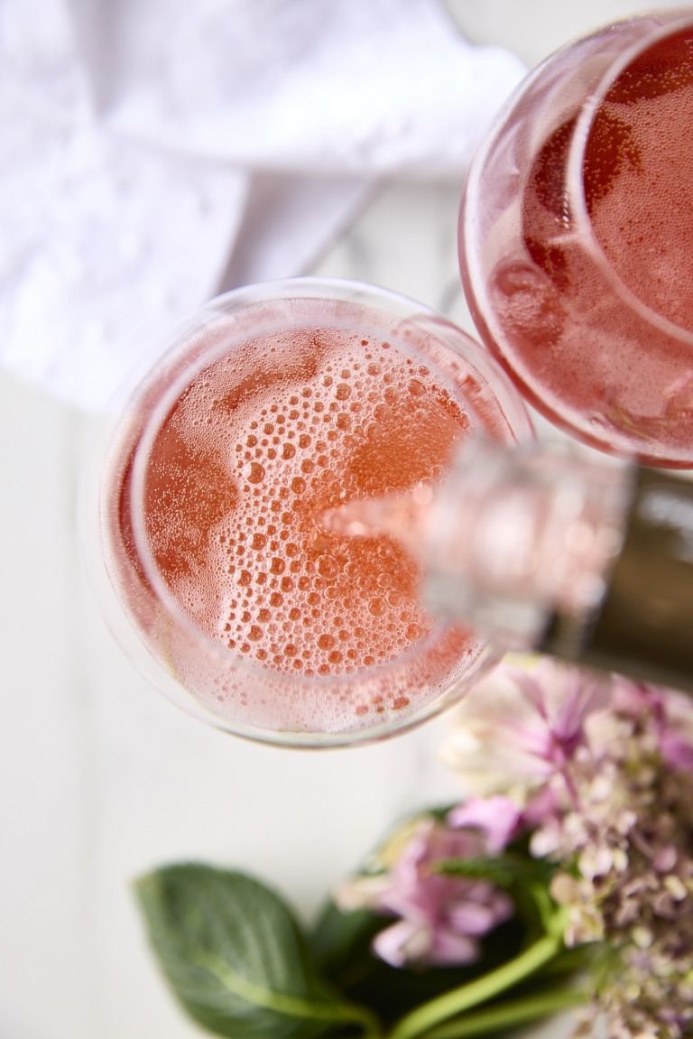 Here’s a strong, SEO-aware alt text that’s descriptive without being stuffed: Alt text: Top-down view of rosé champagne being poured into a glass, bubbles rising in soft light for Lunar New Year 2026 celebration.