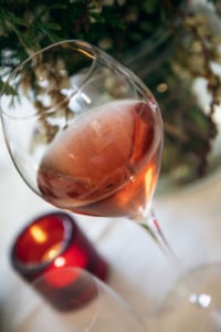 Here’s a full SEO- and editorial-ready set for that image:Alt text: Close-up of rosé champagne in a glass with delicate bubbles rising, beside a flickering red votive candle, evoking warmth, celebration, and Lunar New Year festivity.