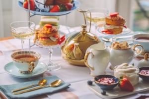 A traditional afternoon tea setting featuring delicate porcelain cups, a teapot and freshly prepared treats.
