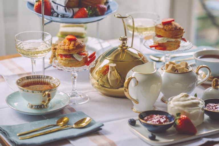 A traditional afternoon tea setting featuring delicate porcelain cups, a teapot and freshly prepared treats.
