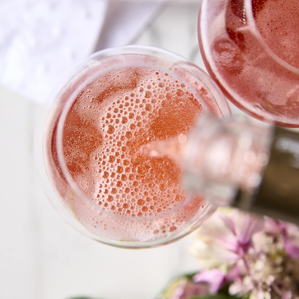 Here’s a strong, SEO-aware alt text that’s descriptive without being stuffed: Alt text: Top-down view of rosé champagne being poured into a glass, bubbles rising in soft light for Lunar New Year 2026 celebration.